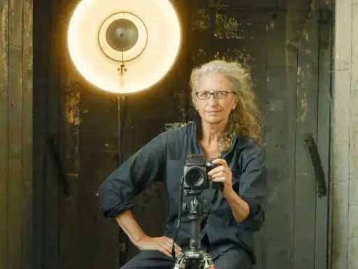 Annie Leibovitz foto: la celebre fotografa con la sua macchina fotografica, illuminata da un grande riflettore.