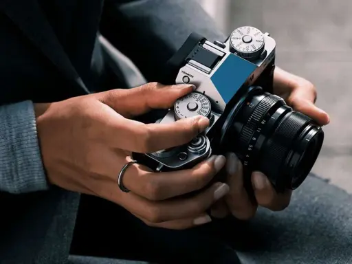 Mani che regolano i quadranti di una fotocamera, con un anello al dito. Immagine fotografica.