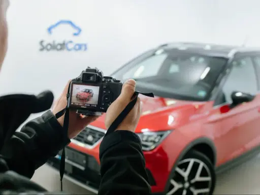 Persona che scatta foto a un'auto rossa ferma, con la telecamera che mostra l'anteprima.