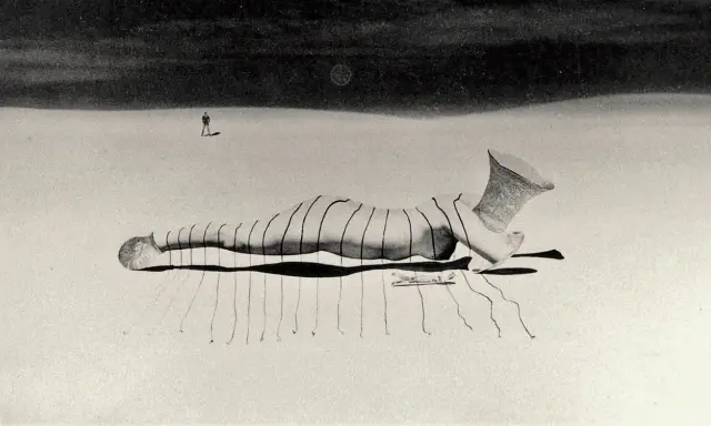 Un uomo solitario osserva una figura distesa, un'opera di un **fotografo surrealista**, con un vaso decorato al posto della testa.