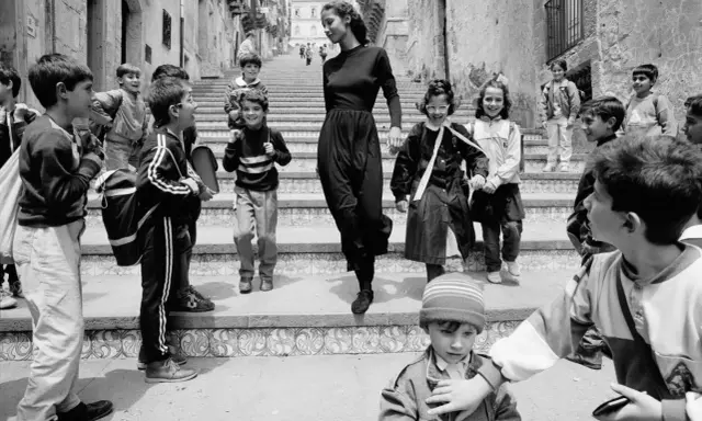 Bambini con zaini scendono una scalinata, accompagnati da una donna elegante. Un'istantanea che cattura la vivacità di queste fotografie famose.