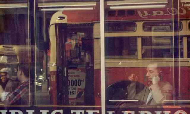 Un uomo al telefono, riflesso su una vetrina, evoca l'atmosfera urbana di Saul Leiter.