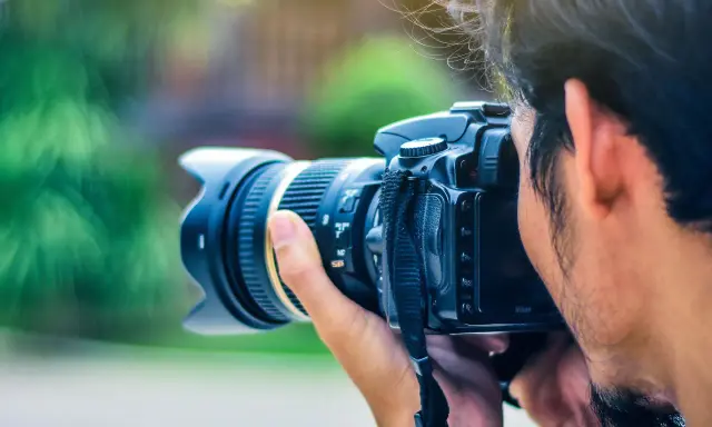 Un fotografo cattura un momento con la sua macchina fotografica reflex, il sole illumina i suoi capelli mossi.