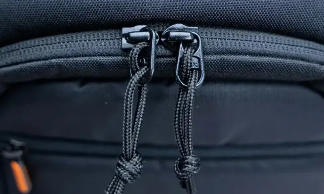 Dettaglio cerniere con cordini di un zaino fotografico Lowepro, pronto per proteggere la tua attrezzatura.