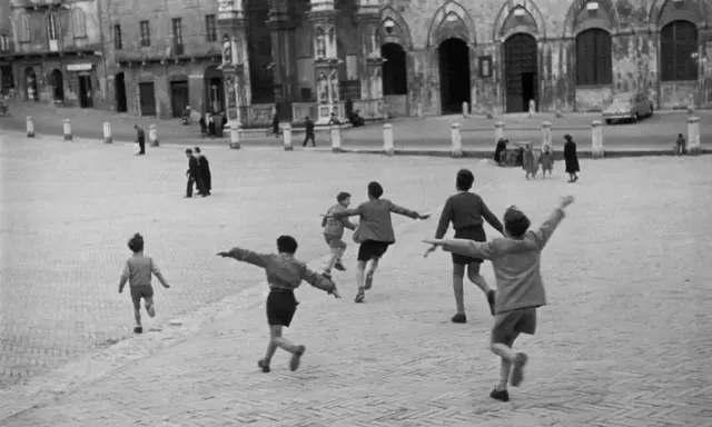 Bambini giocano in una piazza, un momento di street photography famosi.