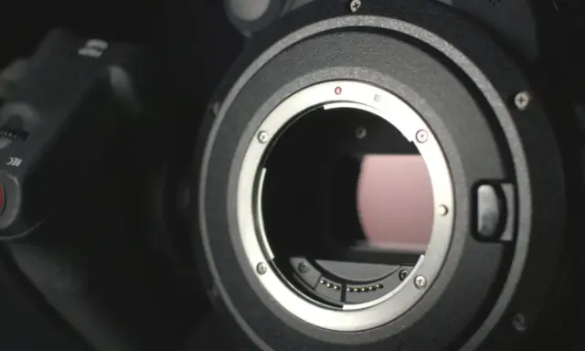 Dettaglio di una fotocamera con attacco obiettivo aperto, mostrando i contatti per i sensori digitali.