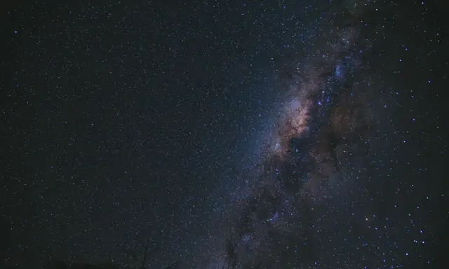 Una foto al cielo notturno, con la Via Lattea che brilla tra innumerevoli stelle.