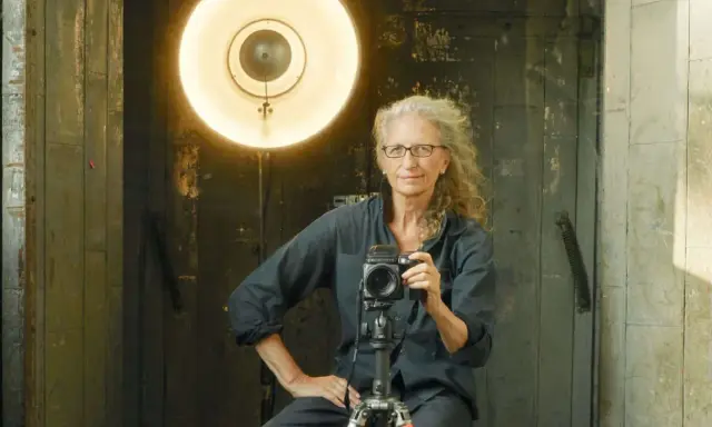Annie Leibovitz foto: la celebre fotografa con la sua macchina fotografica, illuminata da un grande riflettore.