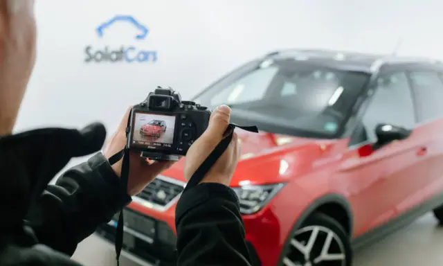 Persona che scatta foto a un'auto rossa ferma, con la telecamera che mostra l'anteprima.