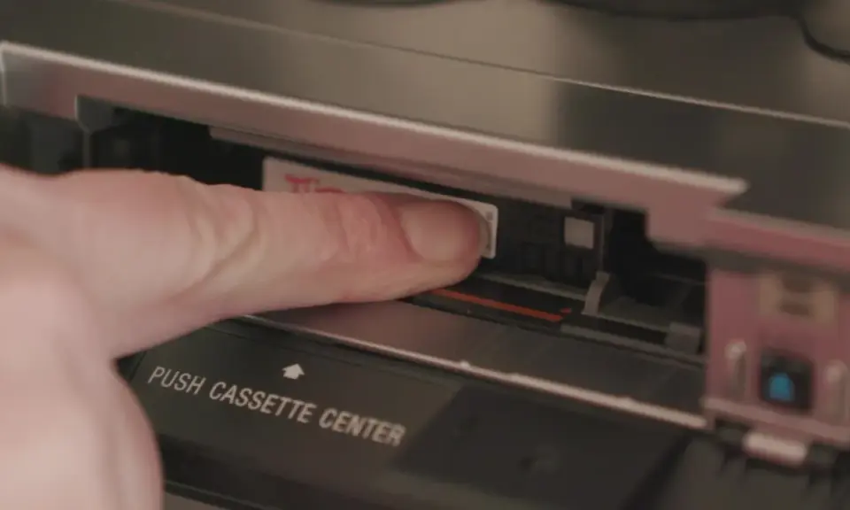 Dito, un dito inserisce una cassetta Hi8 in un videoregistratore, un pezzo di storia delle fotografie.