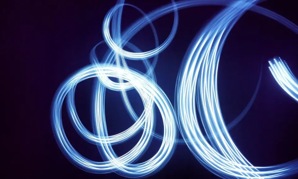 Light painting still life con fili di luce blu che danzano su sfondo scuro, creando un effetto etereo e astratto.