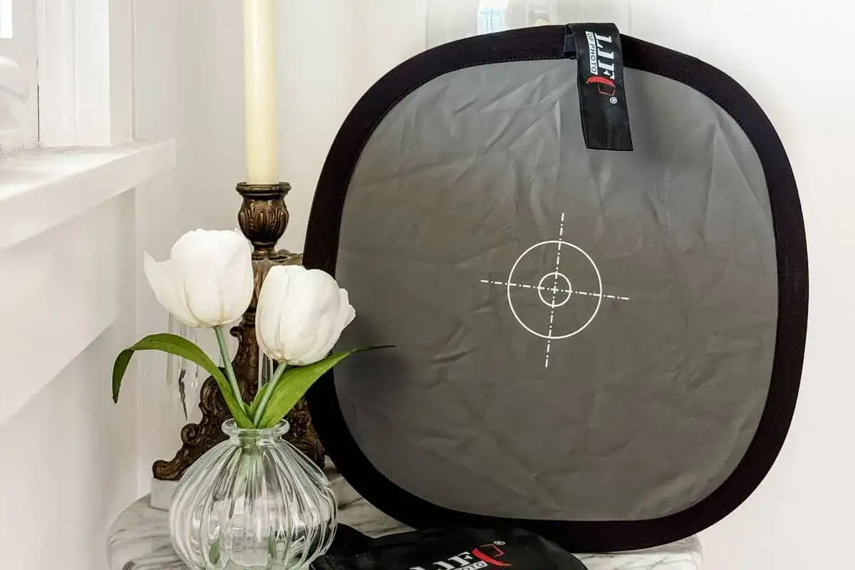 Tavolozza per bilanciamento del bianco fotografia, con tulipani bianchi e candela.