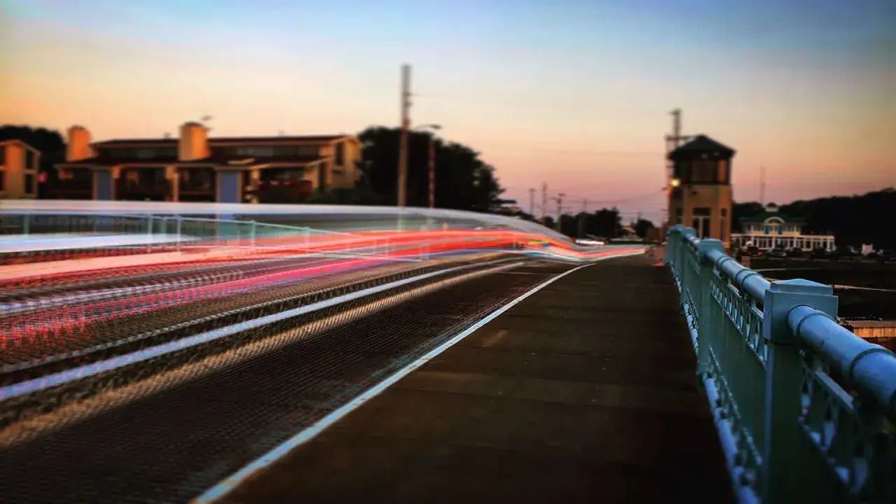 Strisce di luce rossa e bianca su un ponte al tramonto, un effetto ottenuto con lunghe esposizioni per mostrare come fare foto mosse iPhone.