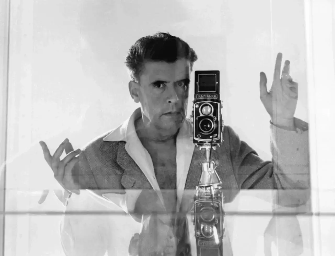 Herbert List si scatta un autoritratto con una Rolleiflex, le mani in posa.