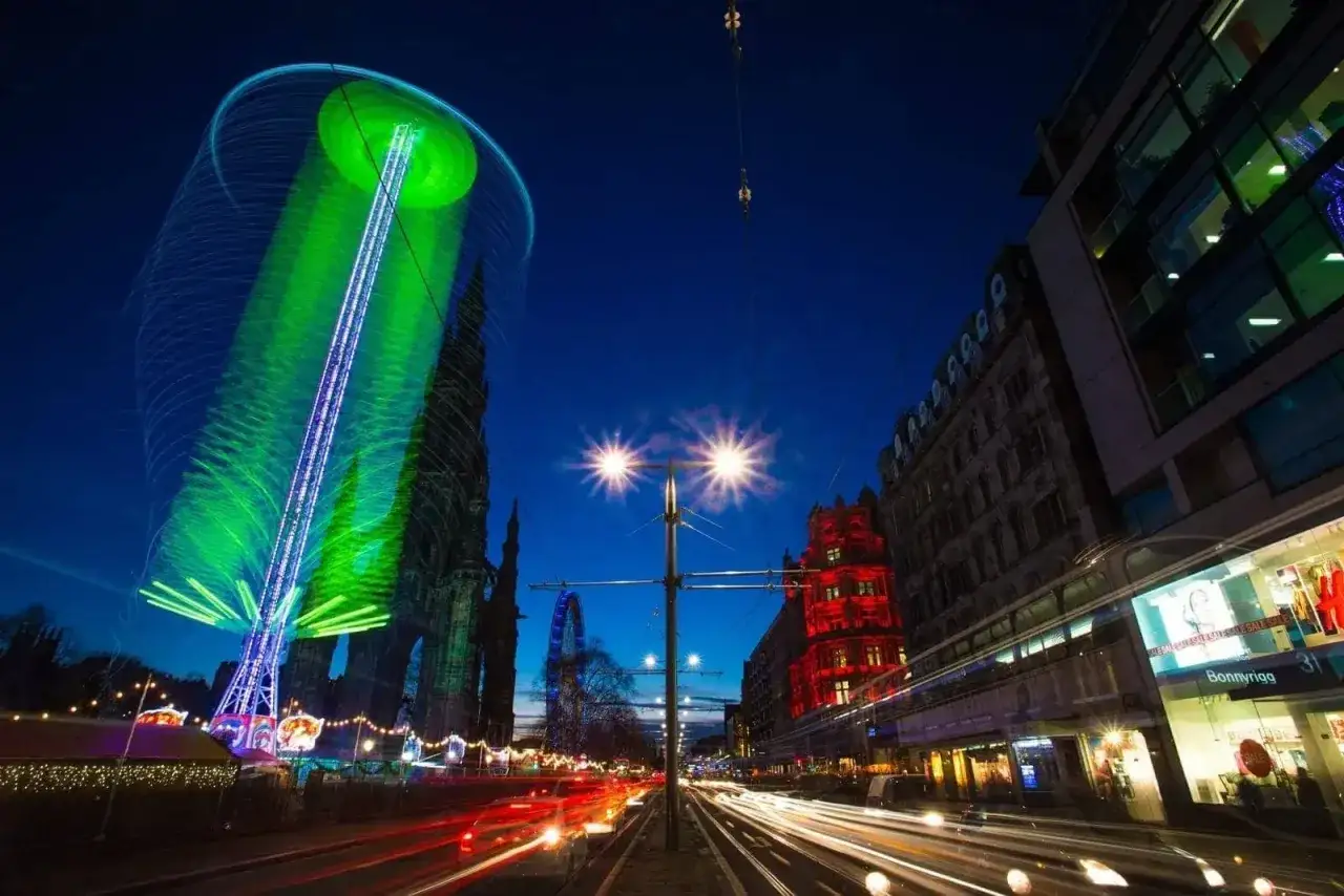 Una foto sera con giostre luminose e scie di luci delle auto. La citt&agrave; &egrave; viva di notte.