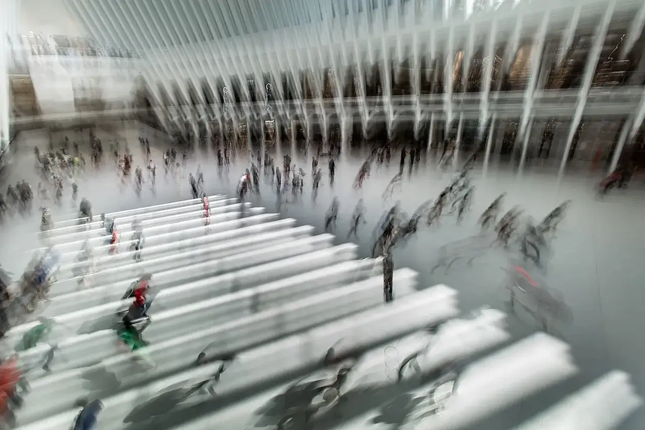 Persone in movimento in una grande hall moderna, con un forte effetto mosso che crea un senso di dinamismo e fluidit&agrave;.