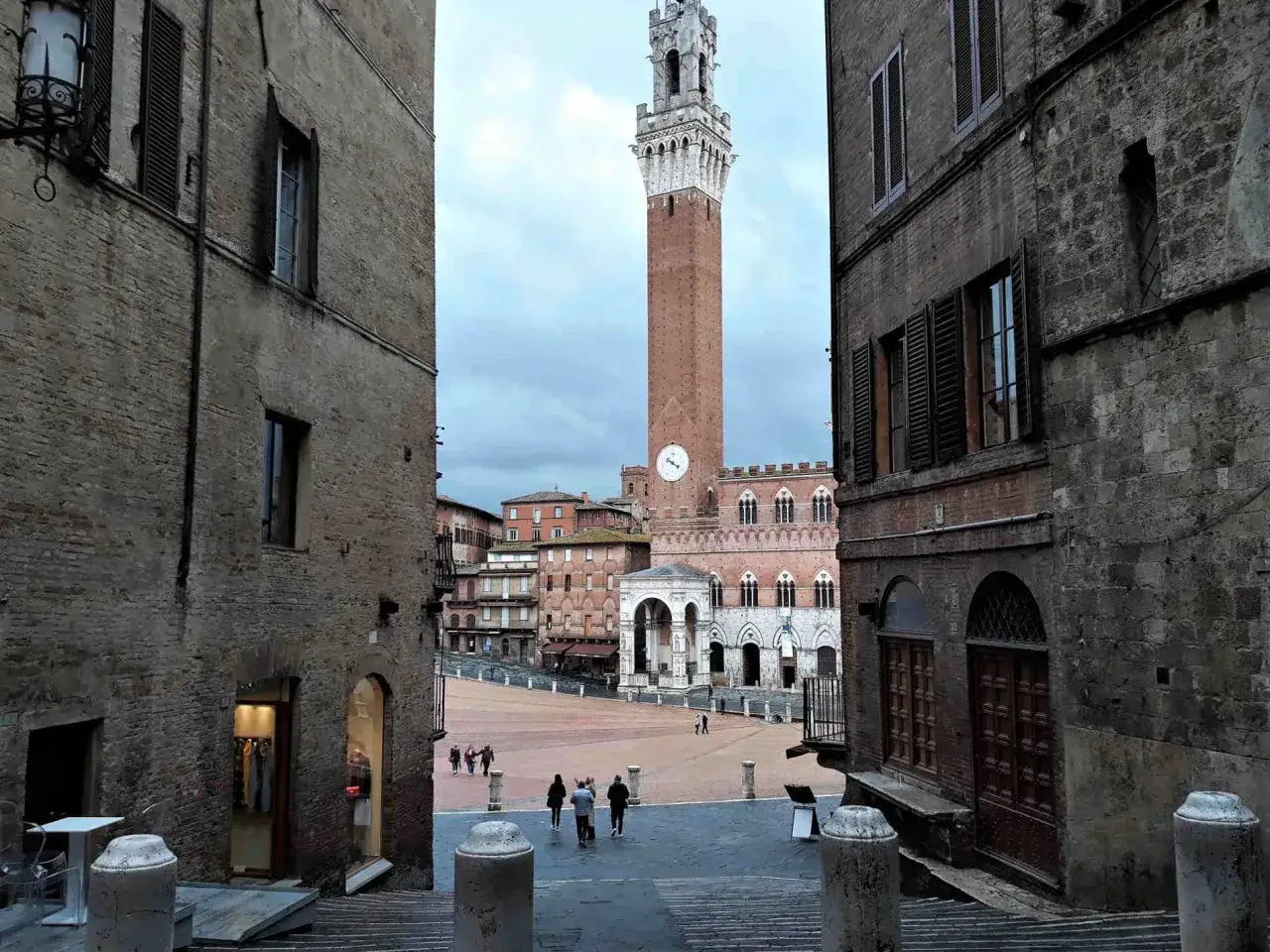 Un vicolo di Siena, con la Torre del Mangia che domina la piazza. Un'istantanea di italia street photography.