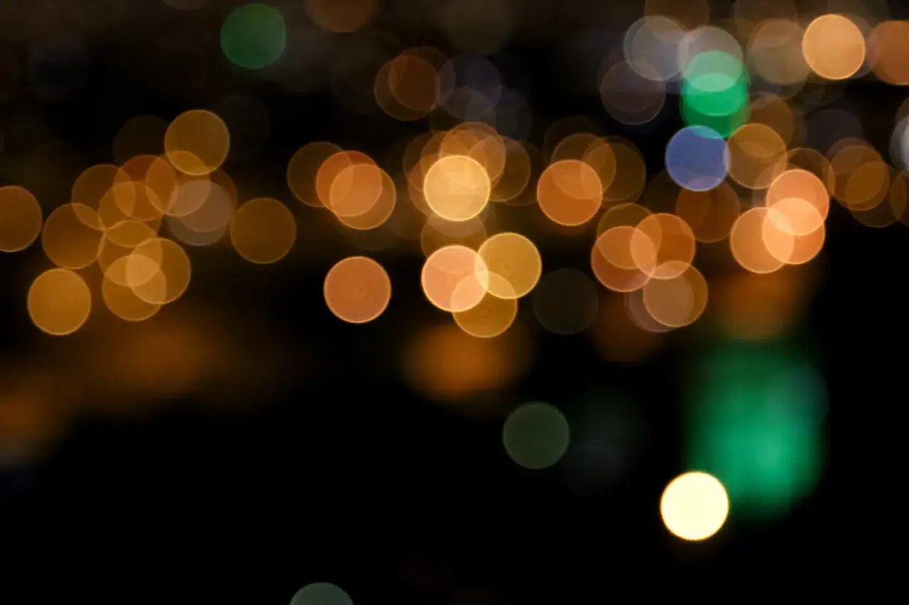Luci sfocate creano un'atmosfera magica, come stelle cadenti dorate e verdi su uno sfondo nero.
