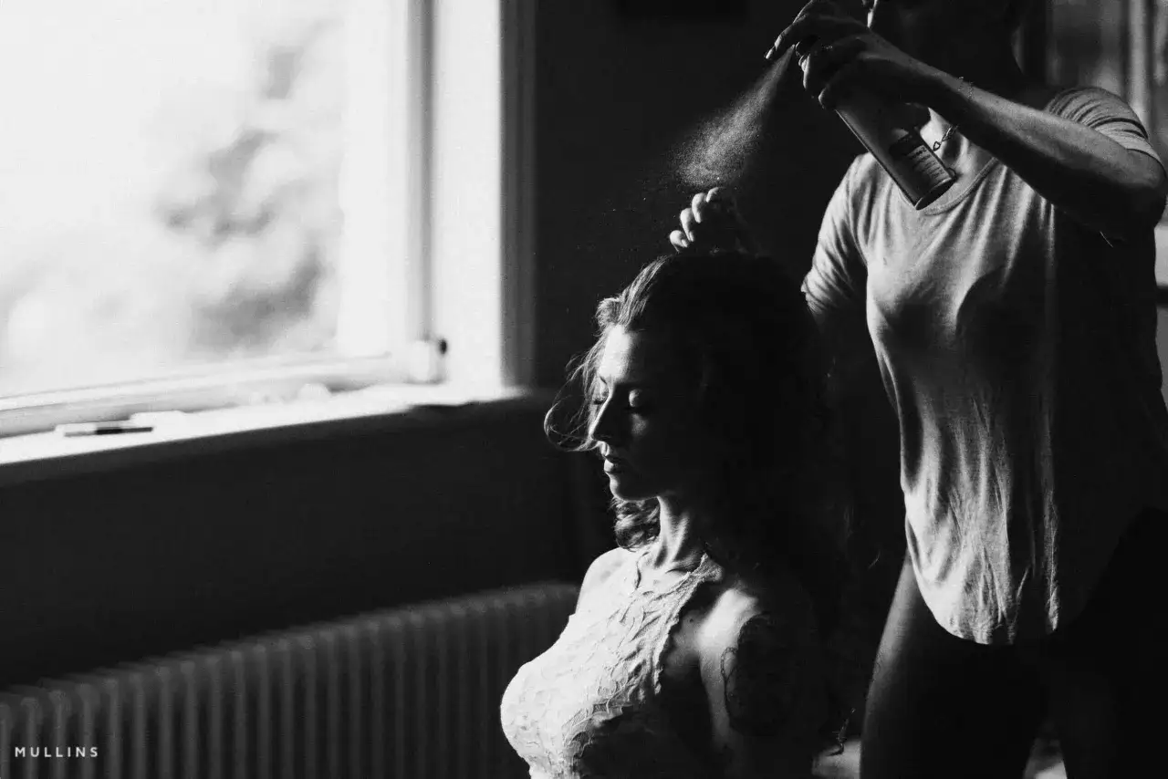 Una donna si prepara, mentre un'altra le spruzza lacca sui capelli. Un momento intimo, quasi un'istantanea di chi ama studiare fotografia da autodidatta.