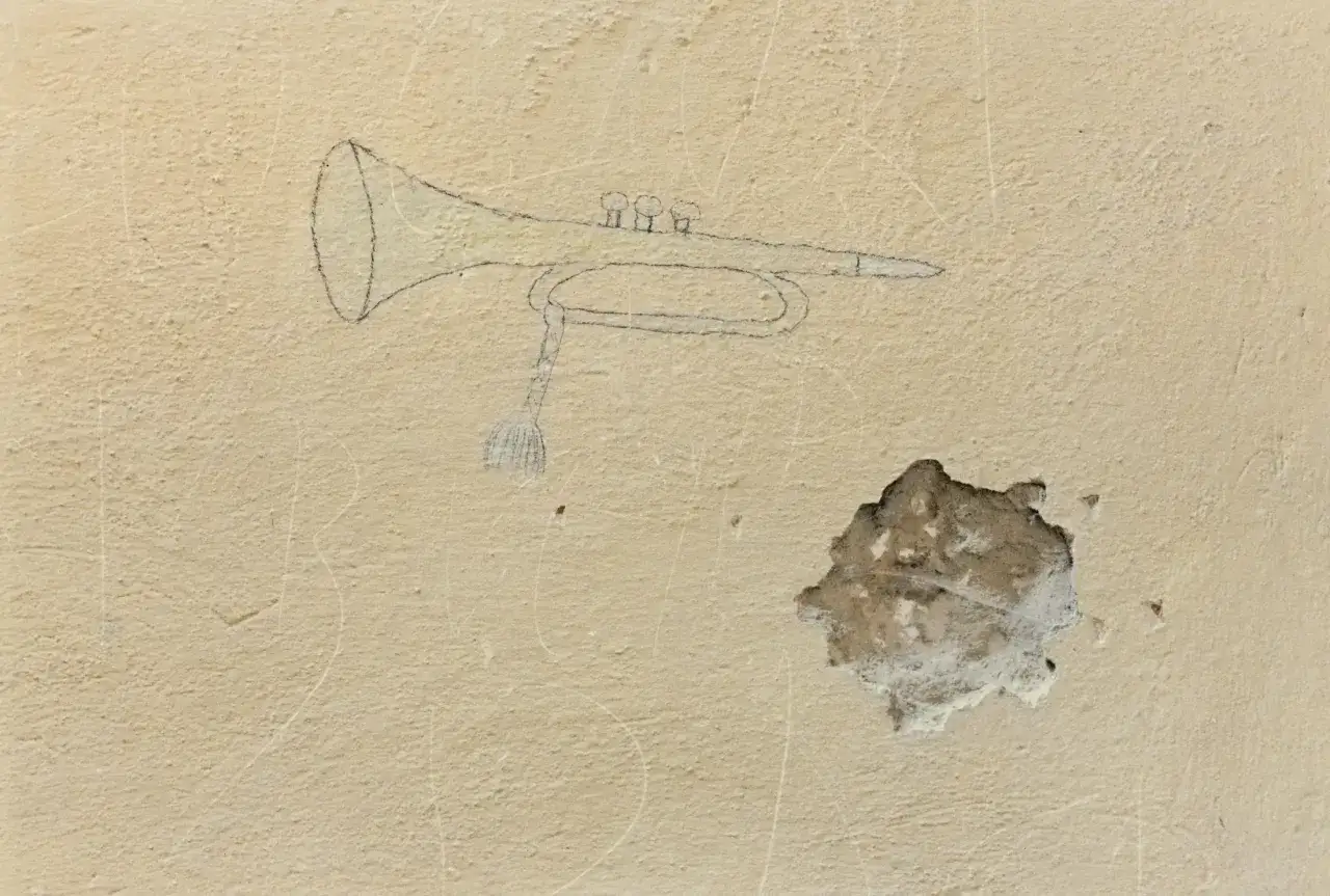 Disegno di una tromba su muro scrostato, un'eco visiva di Luigi Ghirri e Lucio Dalla.