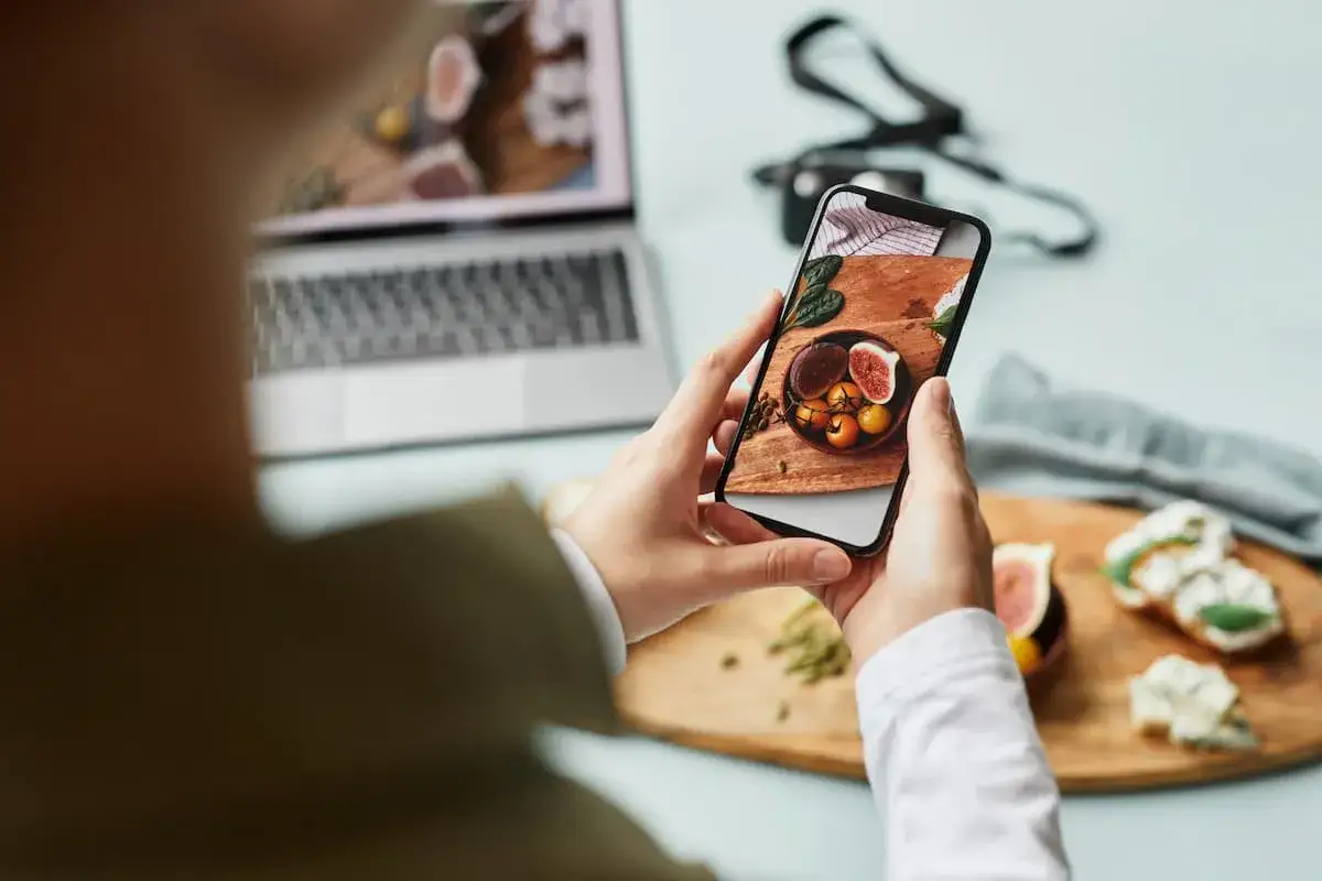 Mani che scattano una foto a un piatto di fichi e pomodorini, un esempio di food photography creativa.