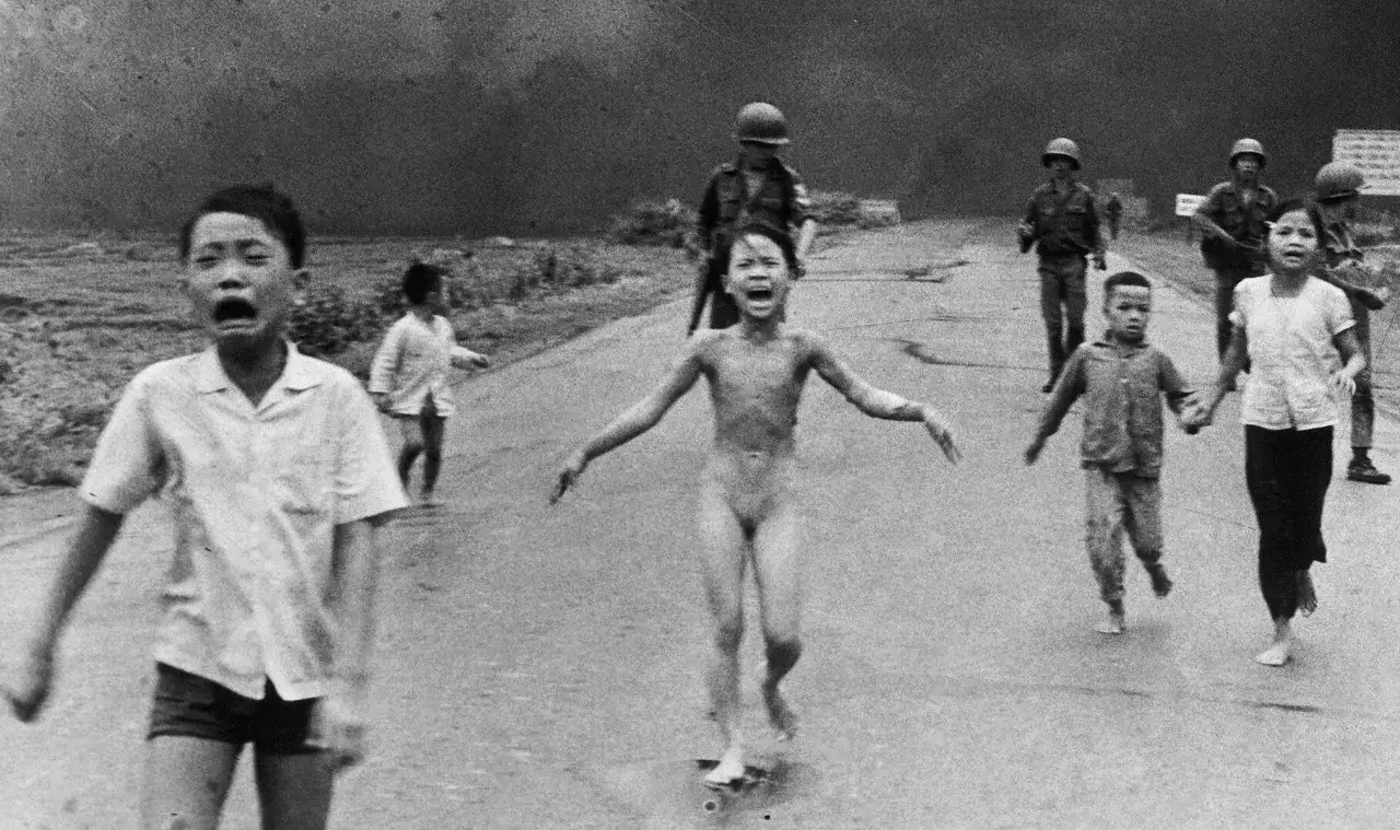 Bambini in fuga, tra cui una bambina nuda, corrono terrorizzati in una strada, un'immagine iconica tra le fotografie famose della guerra.