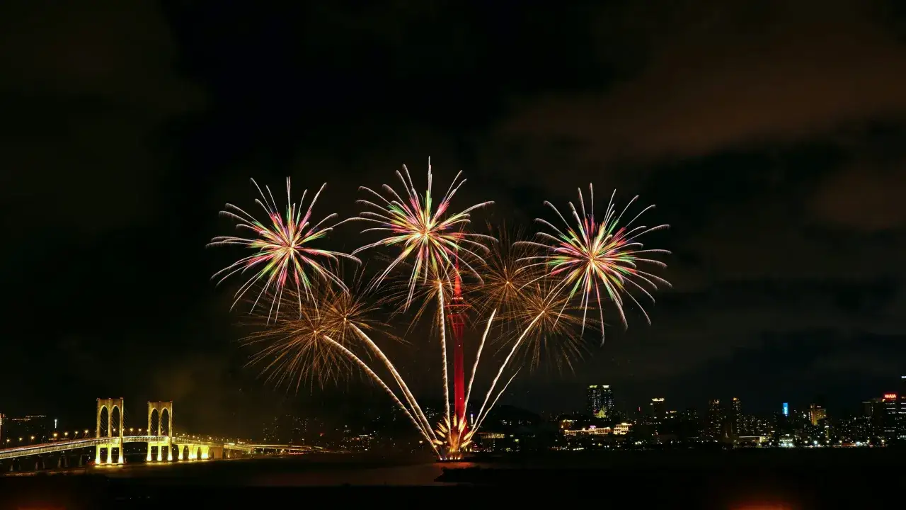 Spettacolare foto fuochi d'artificio illumina il cielo notturno sopra un ponte e una citt&agrave; illuminata.