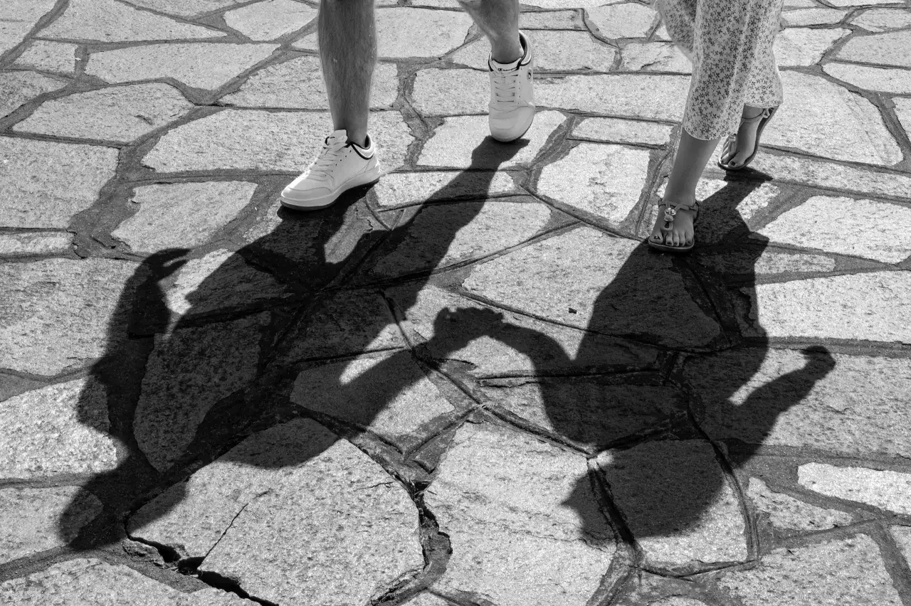 Ombre lunghe su un selciato, un esempio di street photography tecnica. Due figure camminano, le loro ombre si intrecciano.