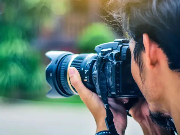 Un fotografo cattura un momento con la sua macchina fotografica reflex, il sole illumina i suoi capelli mossi.